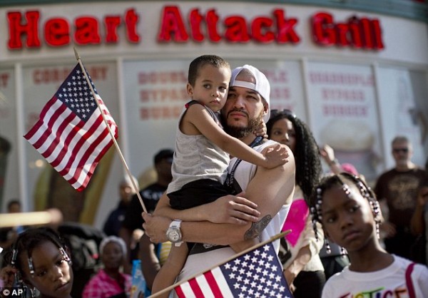 Ulysses Diaz, holds his son, Armani Hinton, as they listen to a speech at a rally in Las Vegas.