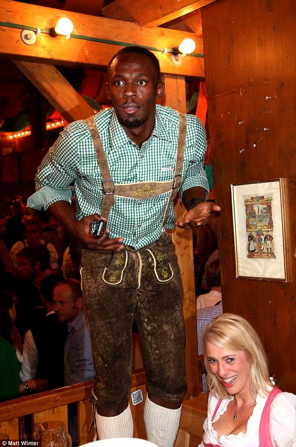 Bolt was seen standing on his chair as he entertained fans at his table in Munich, Germany