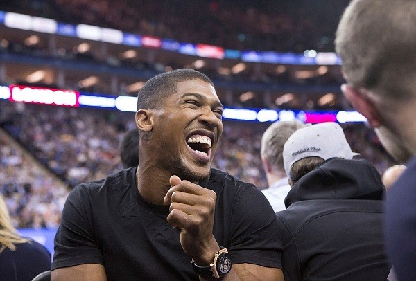 Heavyweight boxer Anthony Joshua laughs with friends during the game, which saw the Bucks beat the Knicks 95-79