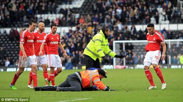 One the pitch-invader is pinned to the ground while Forest's players close in to let their feelings known