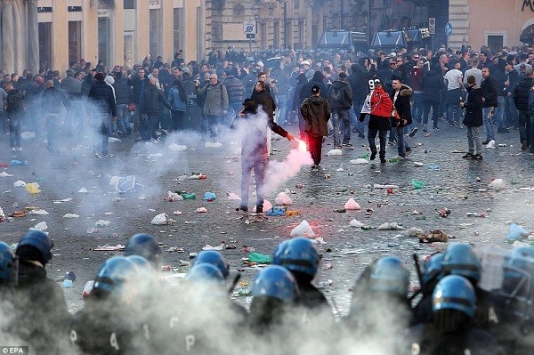 A supporter holds a flare in the middle of a kettle set up by riot police to keep the Feyenoord fans contained