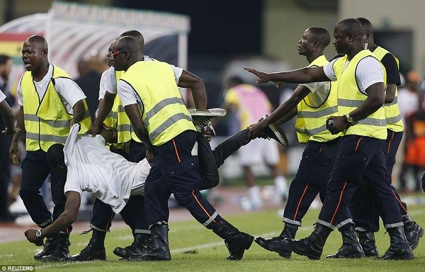 An Equatorial Guinea fan is dragged away by security guards after attempting to storm the pitch during the stoppage in play