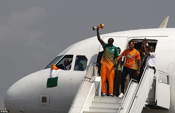 Captain Yaya Toure holds the Africa Cup of Nations trophy aloft on airplane steps after arriving back in Abidjan