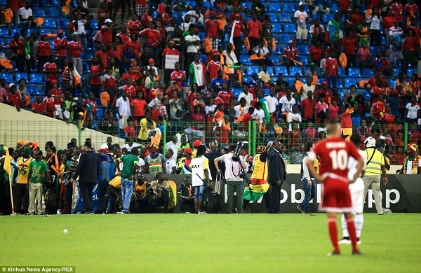 Ghana fans start to make their way onto the running track and the pitch after coming under attack from angry home fans