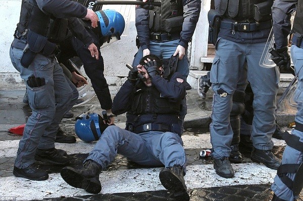 One member of the riot police covers his eyes after his helmet had been knocked off while others support him
