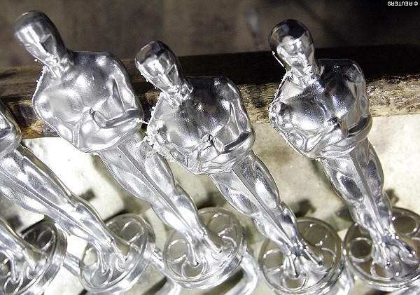 The figure shows a stylized knight wielding a longsword while standing atop a five-spoked reel of film