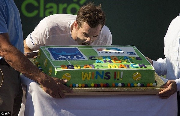 Andy Murray pretends to take a bite out a celebratory cake presented to him after winning his 500th match