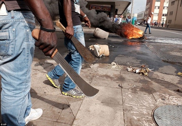 Immigrants carrying machetes have clashed with police in a search for locals that attacked foreign shop owners in Durban