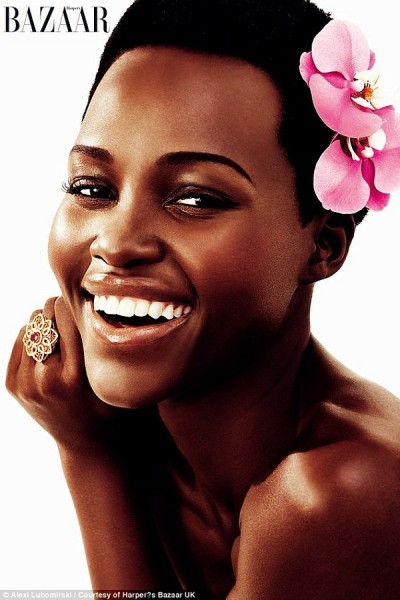 Lupita looks gorgeous in the cover shot for the fashion magazine as she laughs at the camera wearing pink flowers in her hair and a large gold ring