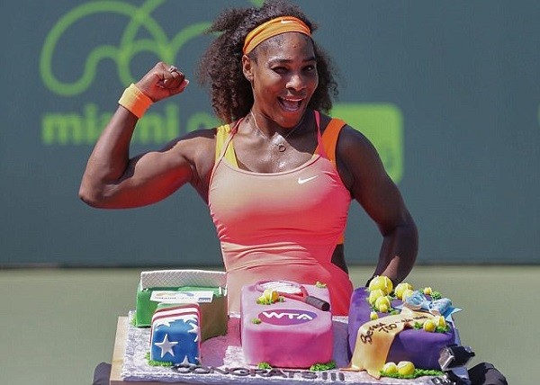 Serena Williams strikes a pose next to her cake after recording her 700th career victory