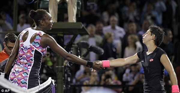 Williams (left) shakes hands across the net with Suarez Navarro as the Spaniard goes through