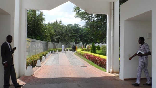 An officer stands guard at the entrance of the residence as a worshiper leaves the chapel