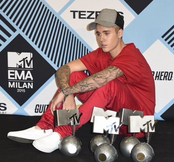 Bieber poses with several award plaques