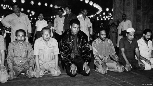 Muhammad Ali observing solat at a mosque during travel.