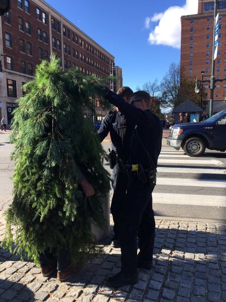 Policemen accost a man in tree costume obstructing traffic