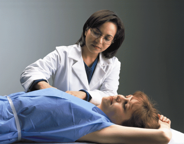 A doctor examines her patient's breast