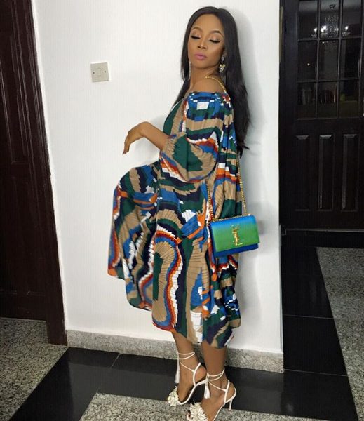 Toke wearing a free flowing gown and a louis vuitton handbag
