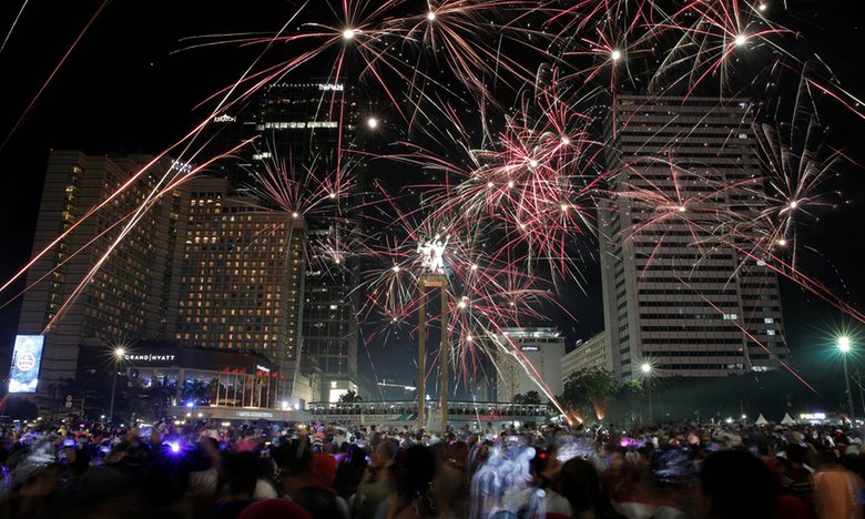 People watch fireworks explode around the Selamat Datang monument during New Year’s Eve celebrations in Jakarta, Indonesia. Photograph: Beawiharta/Reuters