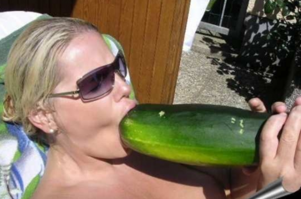 Woman suggestively stuffing a cucumber down her mouth